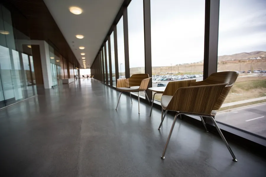 Bright interior corridor with full-height glazing and lounge chairs