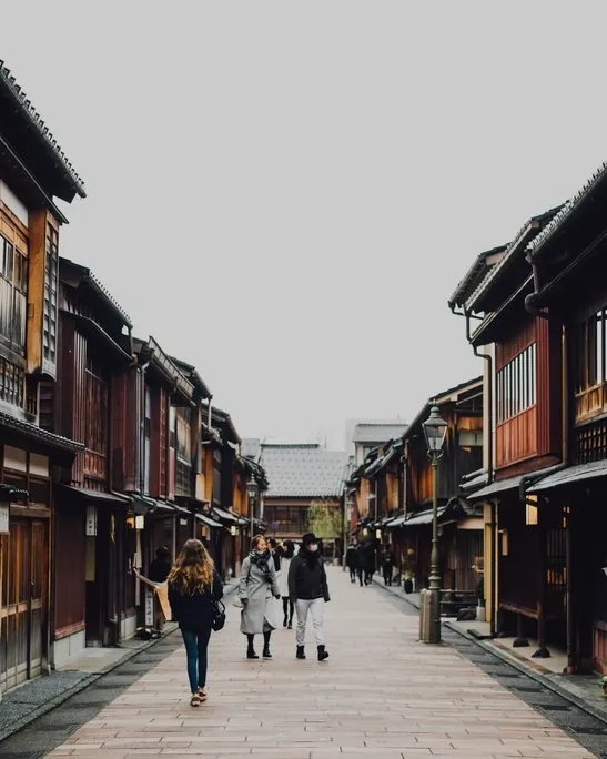People walking along a quiet street lined with timber buildings