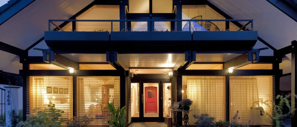 House with timber and glass facade, warmly lit at dusk
