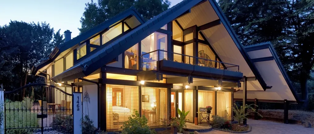 Contemporary house with large glazed gables lit at dusk