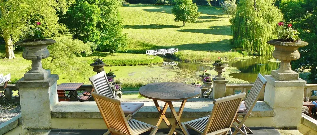 Shaded stone terrace overlooking a green garden and trees